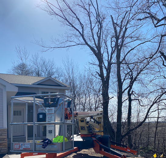 Photo shows job site preparation with a lift before tree removal