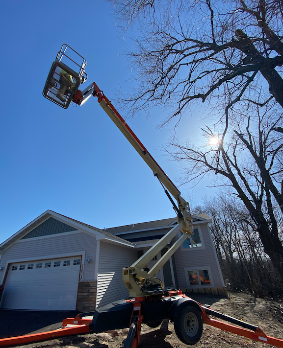 Photo shows tree removal project starting with lift in the air